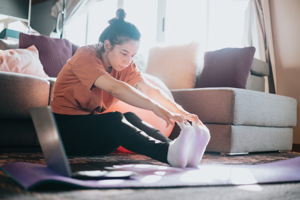 Une femme fait des étirements après une séance de sport à la maison.