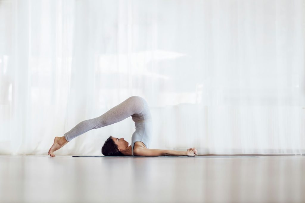 Une pratiquante de yoga effectue une posture avec la tête au sol.